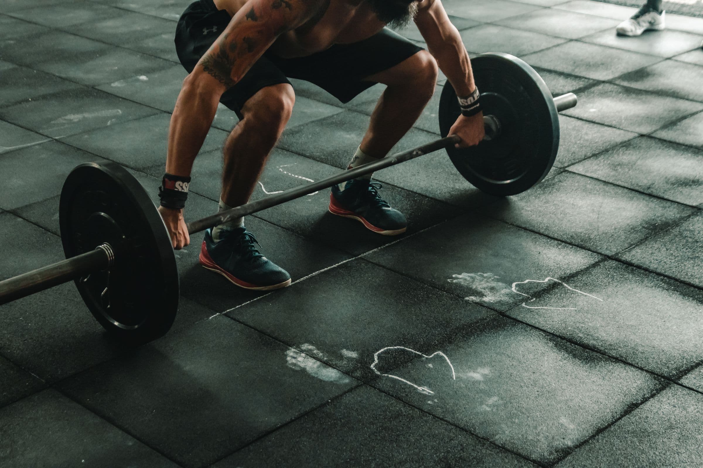 An athlete setting up for a deadlift on a chalk-marked gym floor